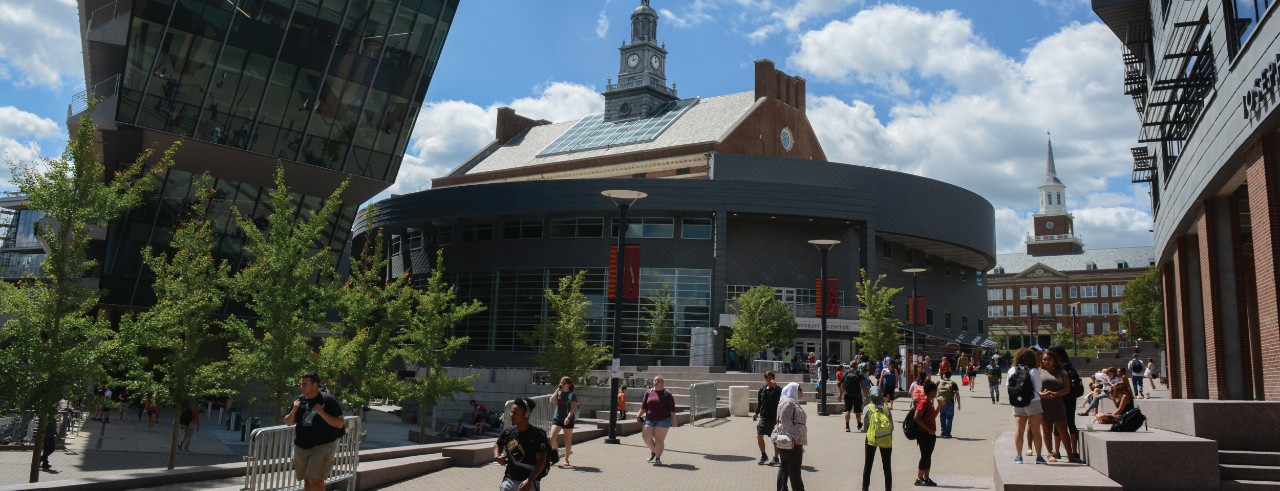 UC MainStreet scene with students walking along pavered pathway between buildings.