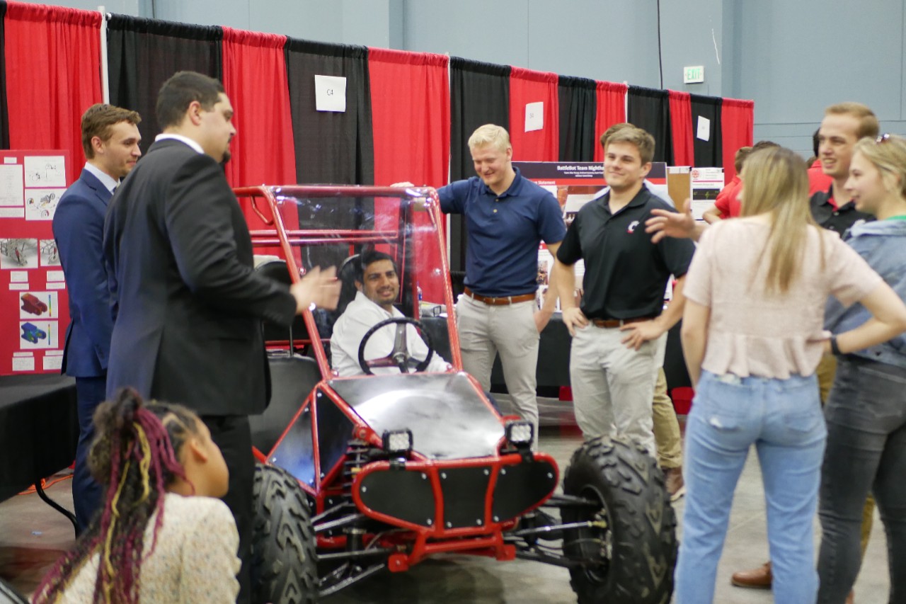 a group of people look at a go kart in a conference hall
