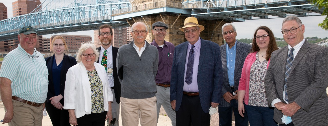 group of people standing in front of a bridge along the riverfront