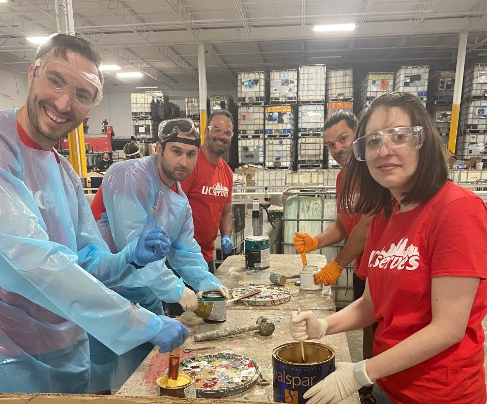 UC Online employees stir paint at Matthew 25: Ministries 