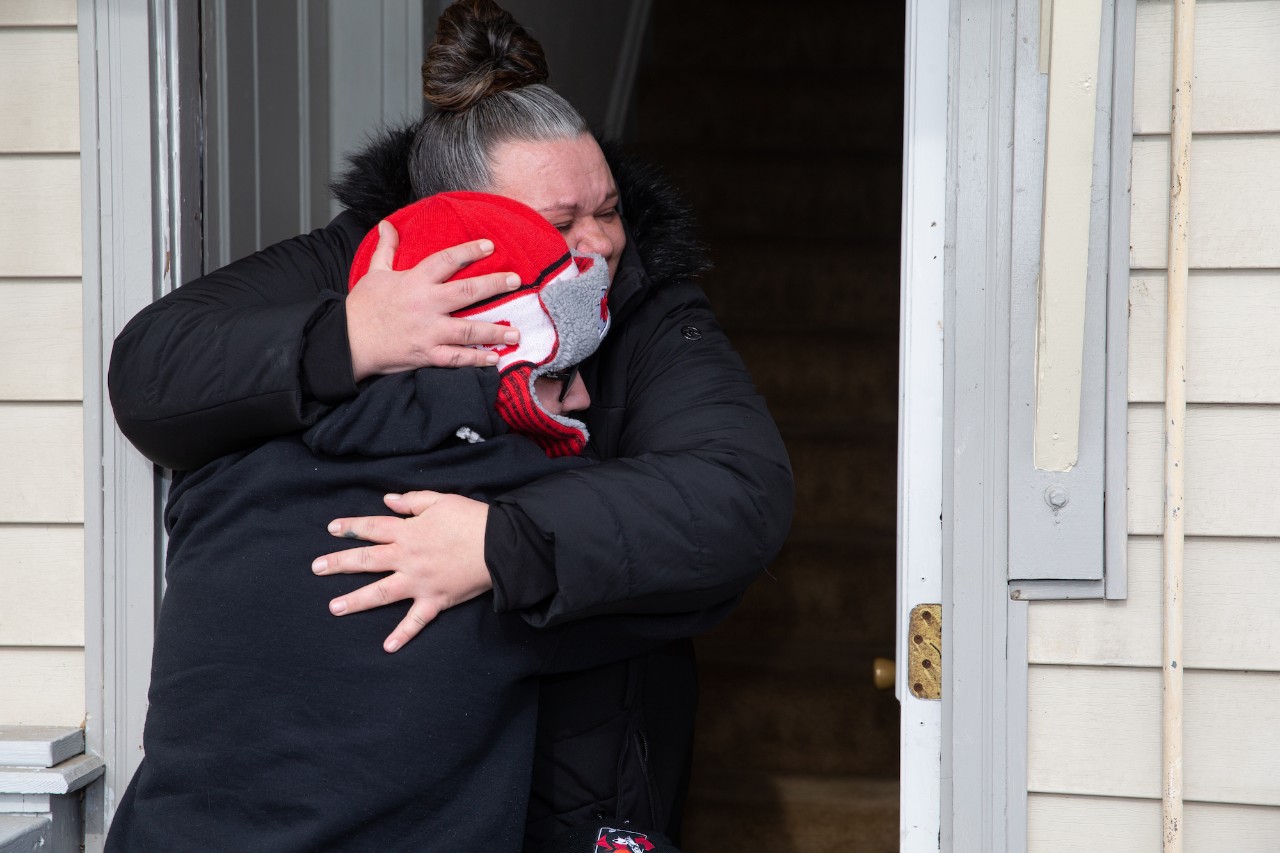 Mother, Amanda Taylor, hugging her son, Marcus Elliott, in a doorway