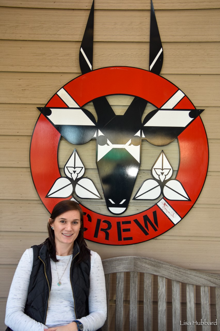 Julie Barnes poses in front of the CREW logo.