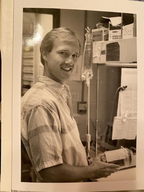 John Klaserner smiles while holding pharmacy equipment in a yearbook photo