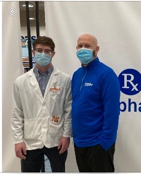 Adam and John Klaserner, wearing masks, stand and smile