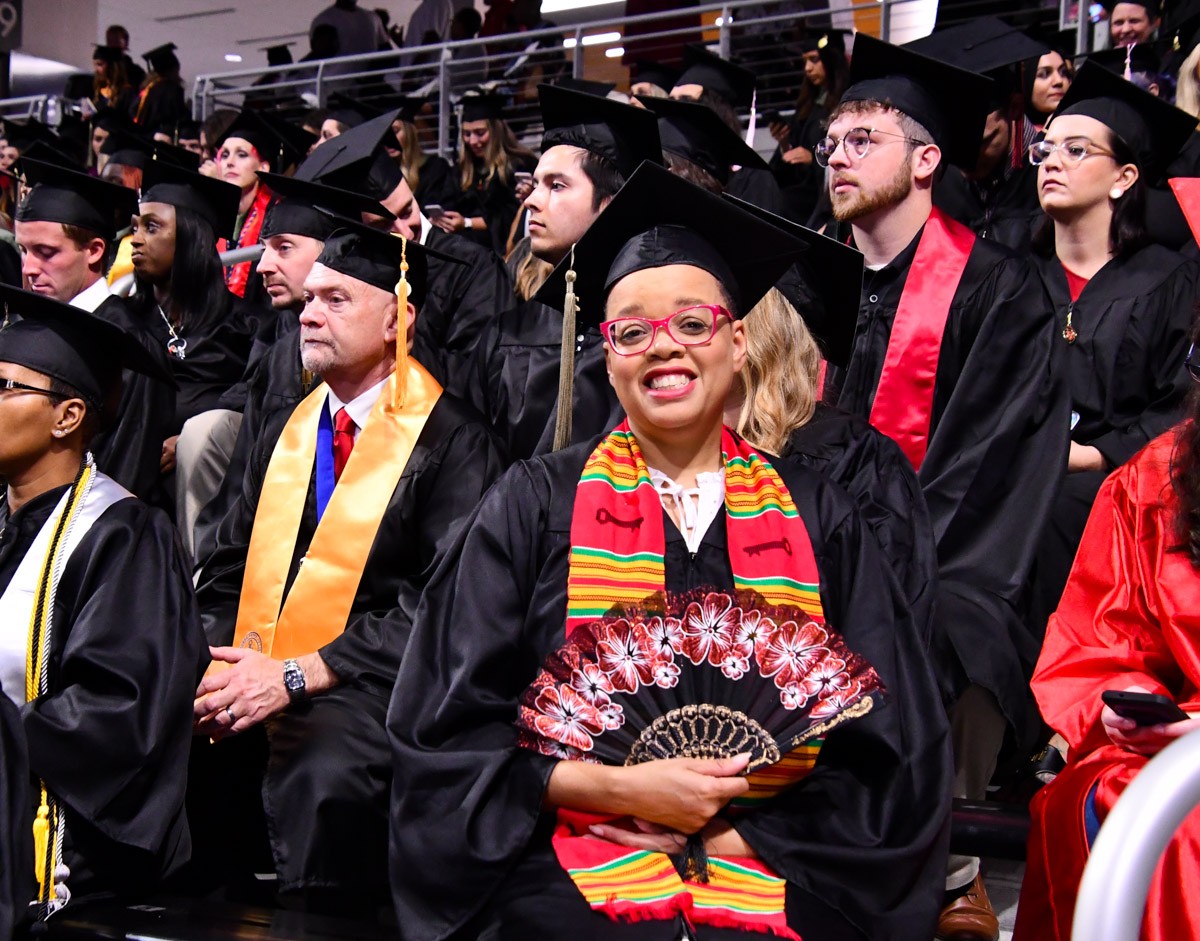 A grad spreads a fan in front of her.