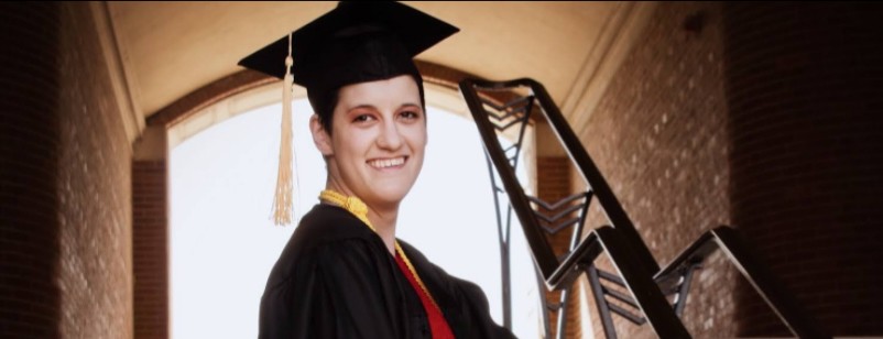 Asia Werner in her commencement regalia posing for a photo on UC's campus