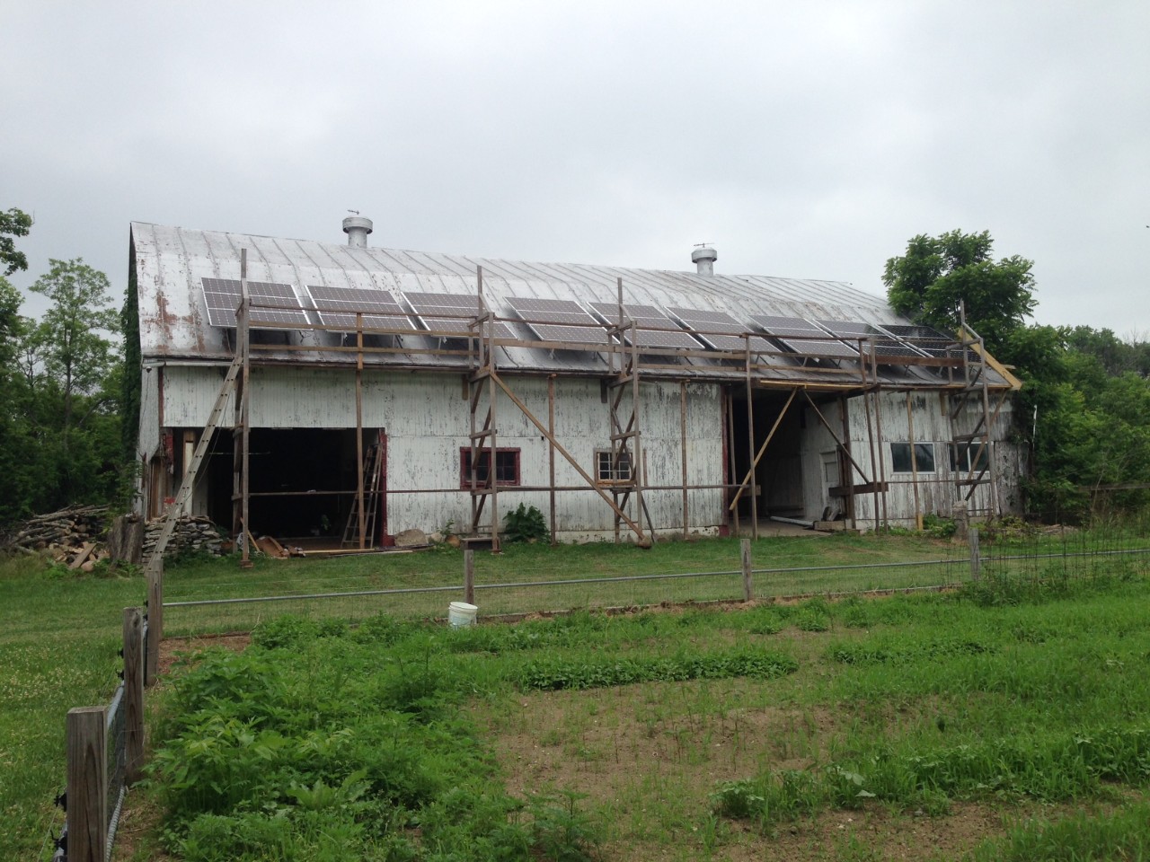 A scaffolding and solar panels cover an old barn.