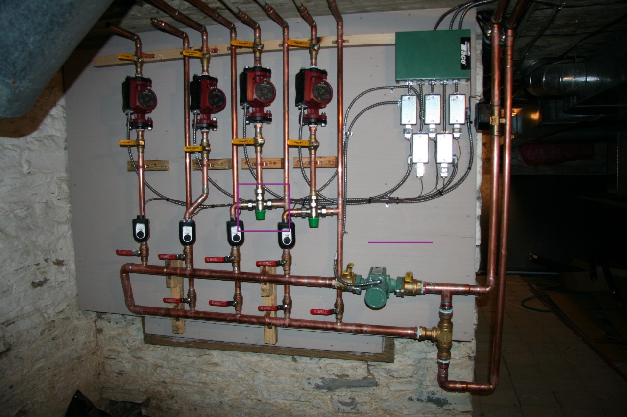 An array of copper pipes and pumps are attached to a wall.
