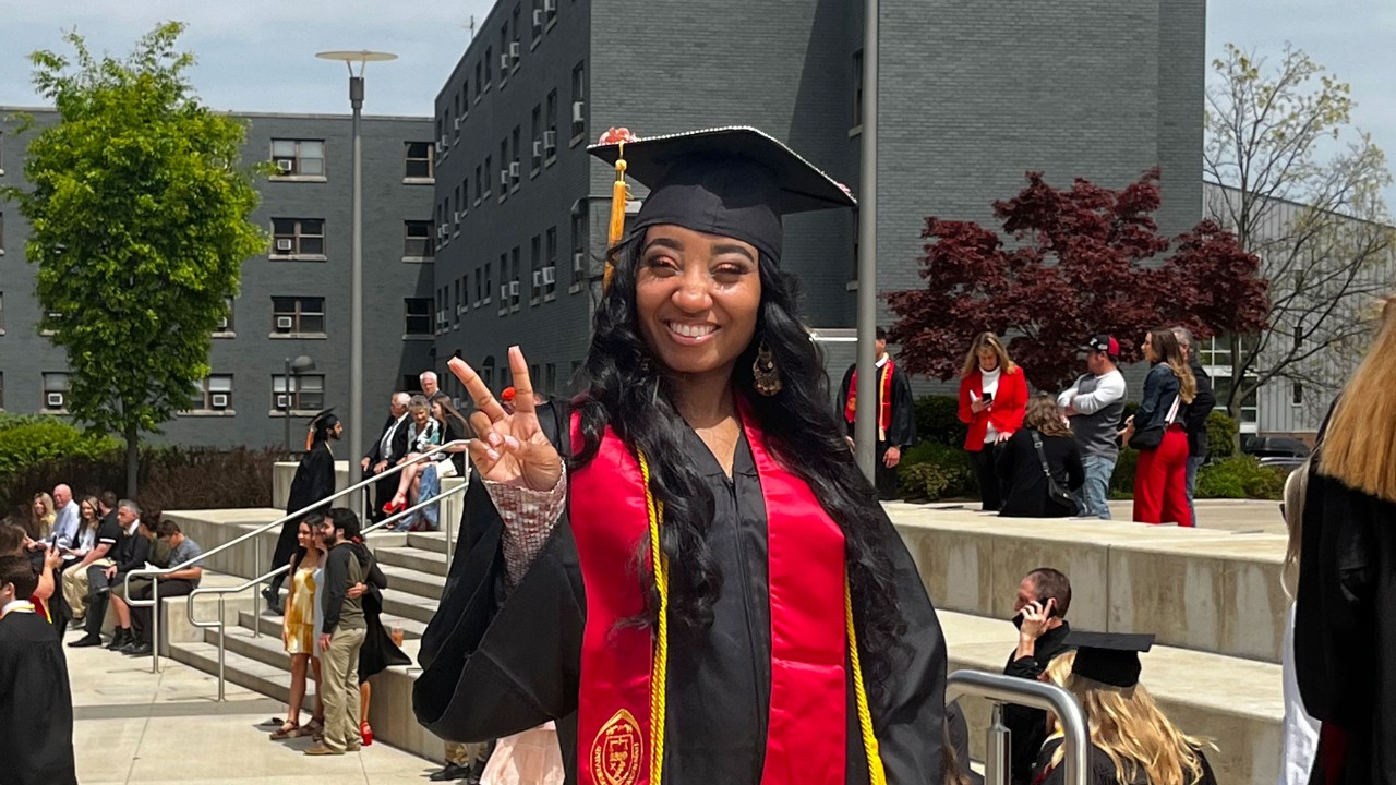 Erica Gary in her Commencement cap and gown on UC's campus