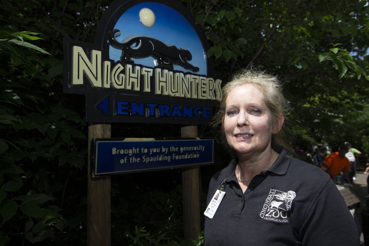 Laura Carpenter stands in front of the Night Hunters sign at the zoo.