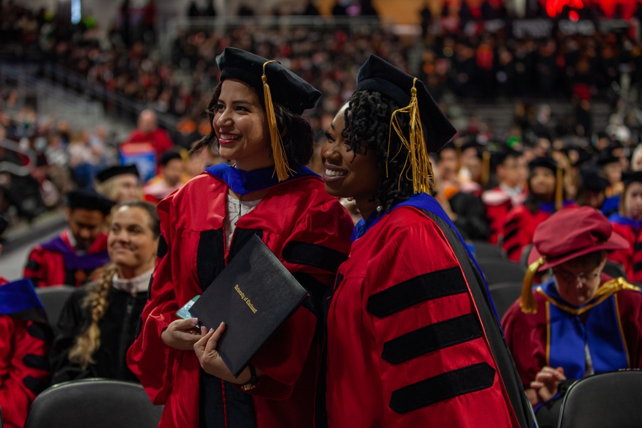 Graduates in matching caps and gowns pose for a photo at Fifth Third Arena.