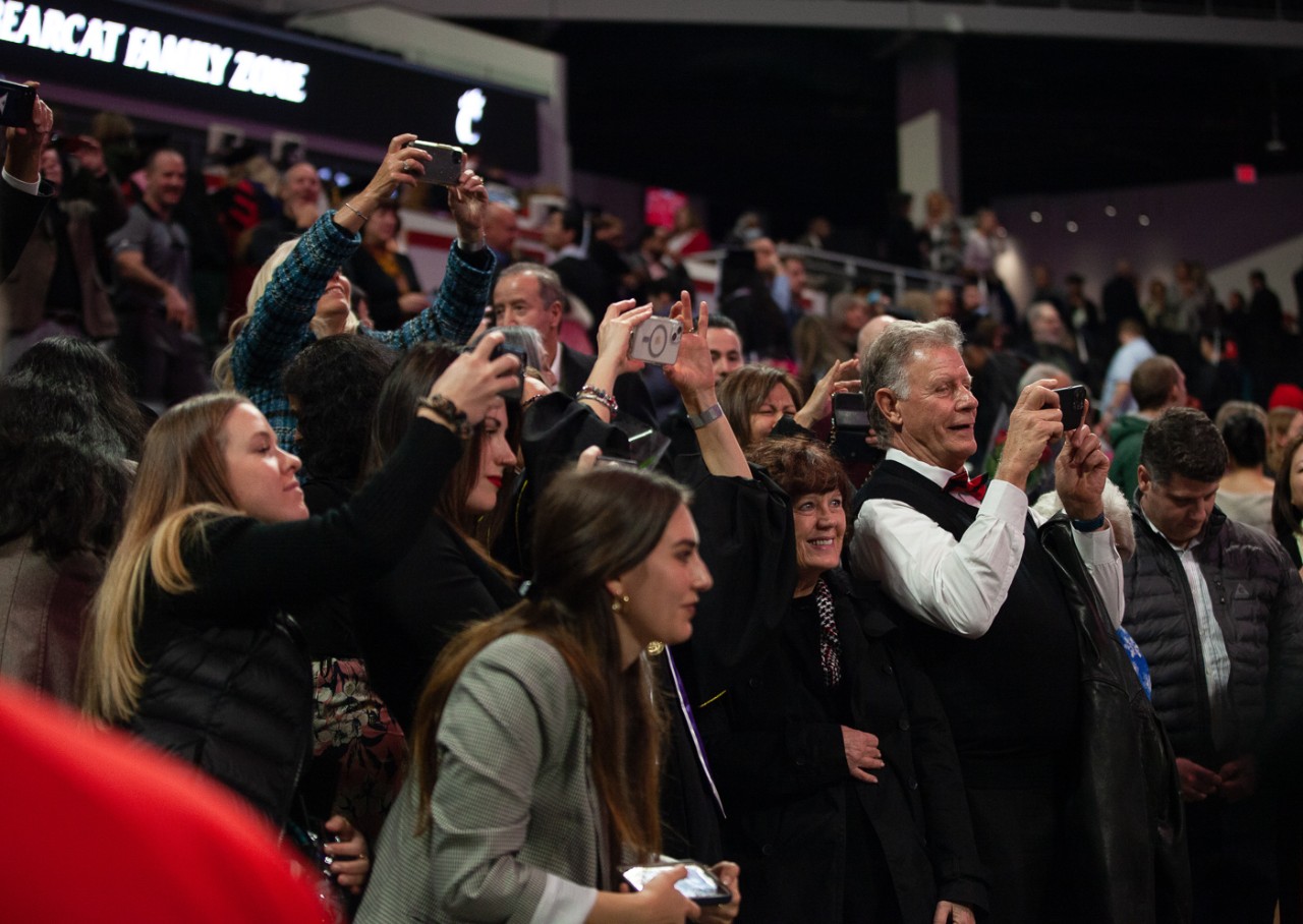 A group of family members all holding cell phones take photos from their seats.