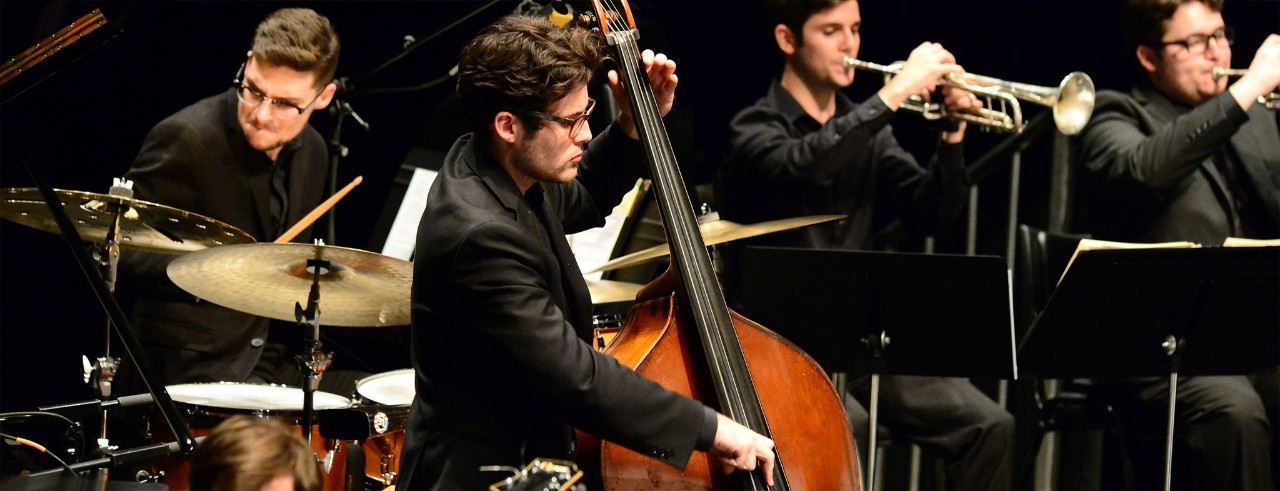 Four musicians playing drums, bass and trumpet.