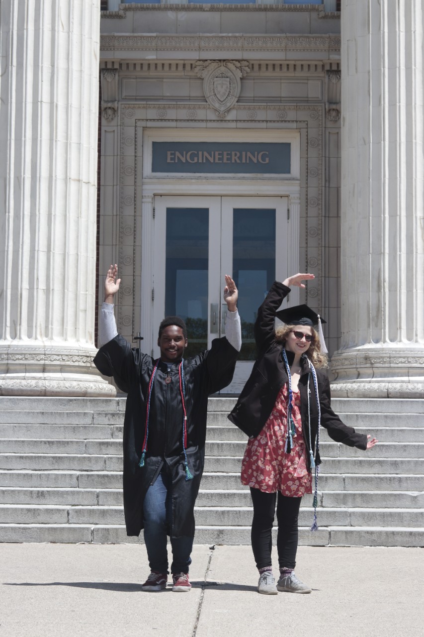 Zoe Lee and Christian Charles form a UC with their arms in front of UC's Baldwin Hall. 