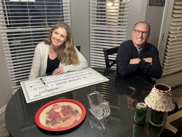 two people sitting at table with big check