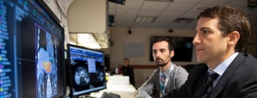 Two doctors sit and review data on a computer screen