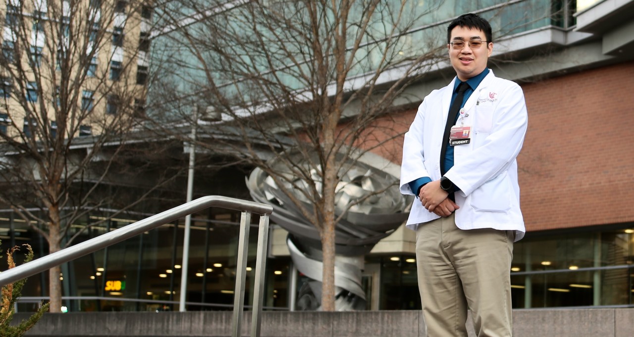 UC med student Minh Nguyen stands in front of UC's College of Medicine on Eden Avenue.