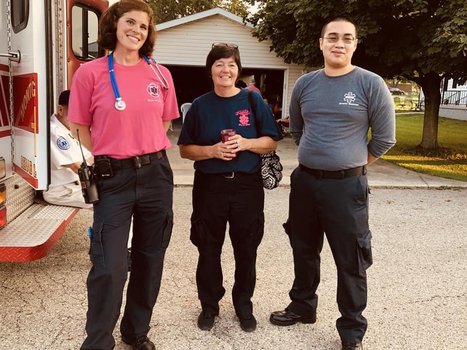 UC's Minh Nguyen (far right) stands with two women as a team of EMT workers.