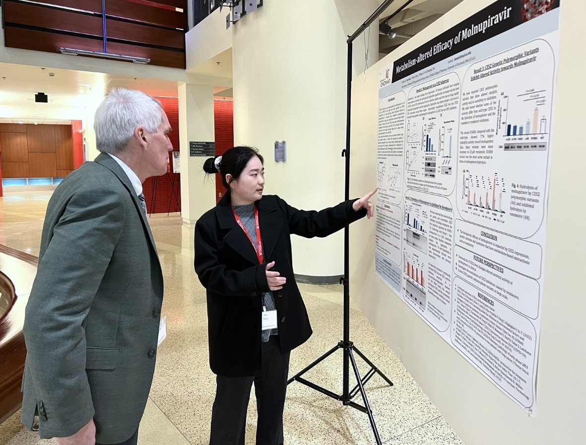 Female student discusses poster with faculty judge at a pharmacy conference.
