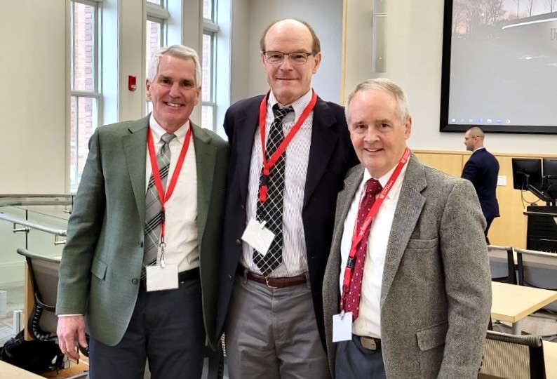 Three men stand together at a pharmacy conference.