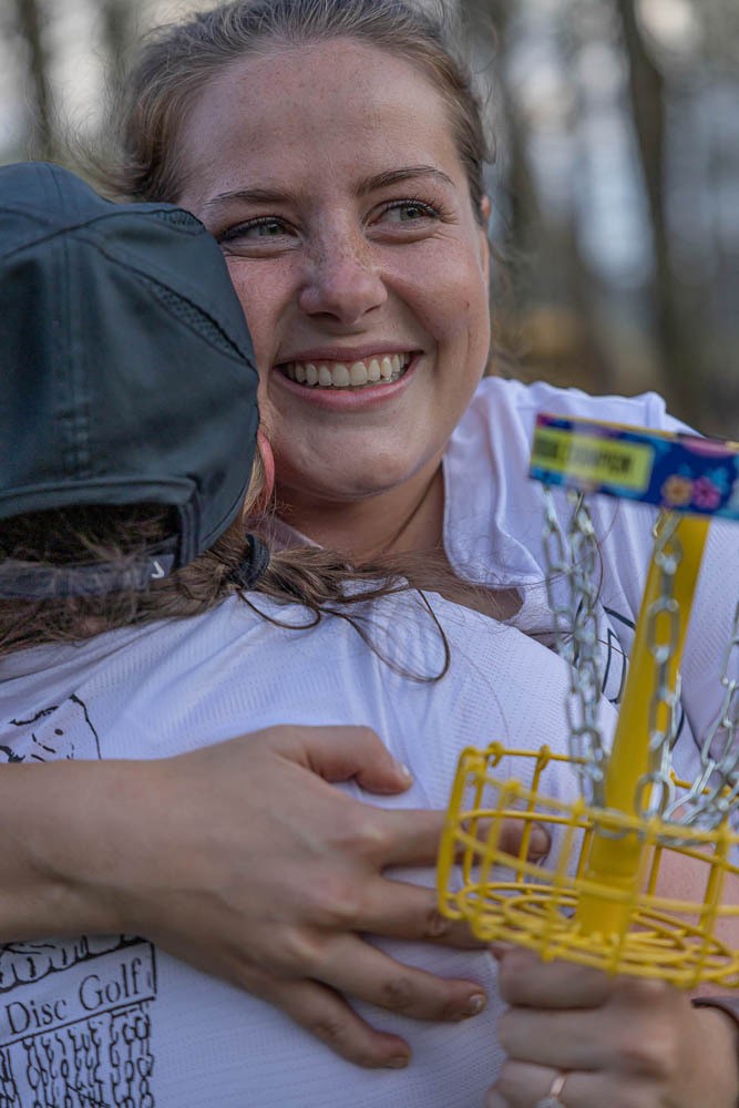 Two players hug while one holds a trophy.