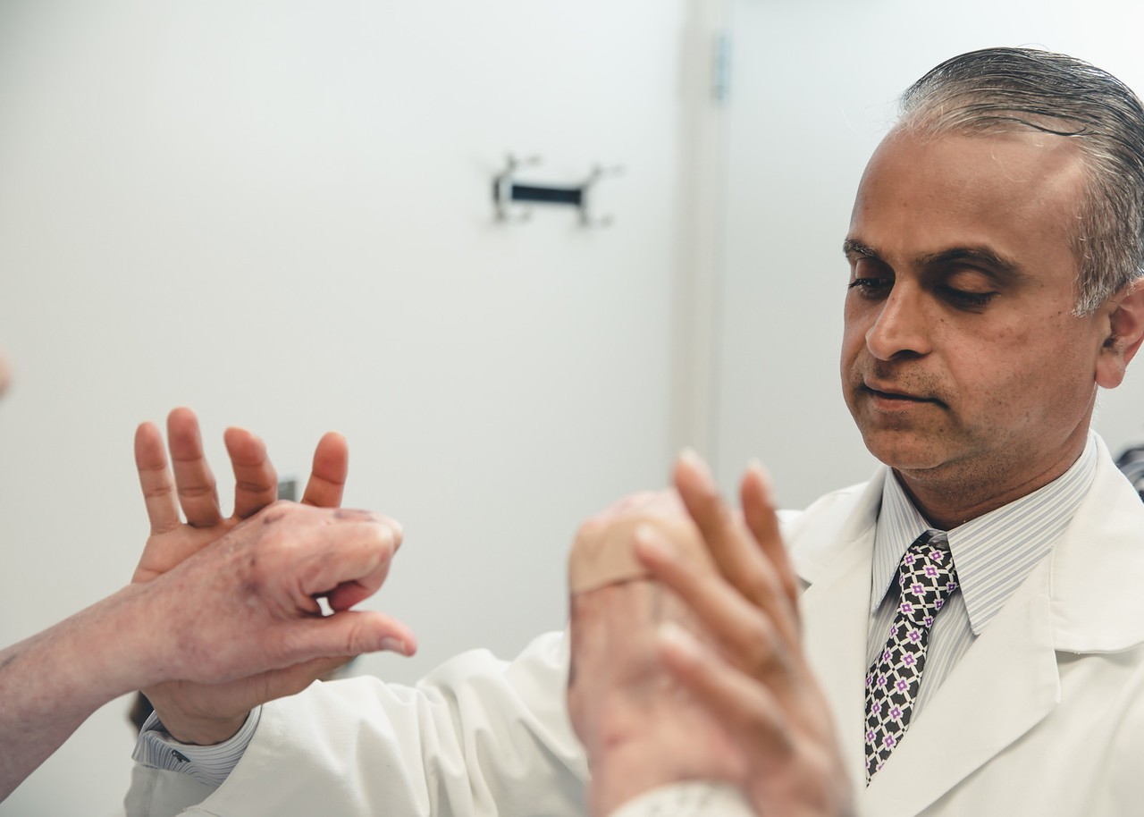 Dr. Ahmad pushes on a patient's outstretched hands in an exam room
