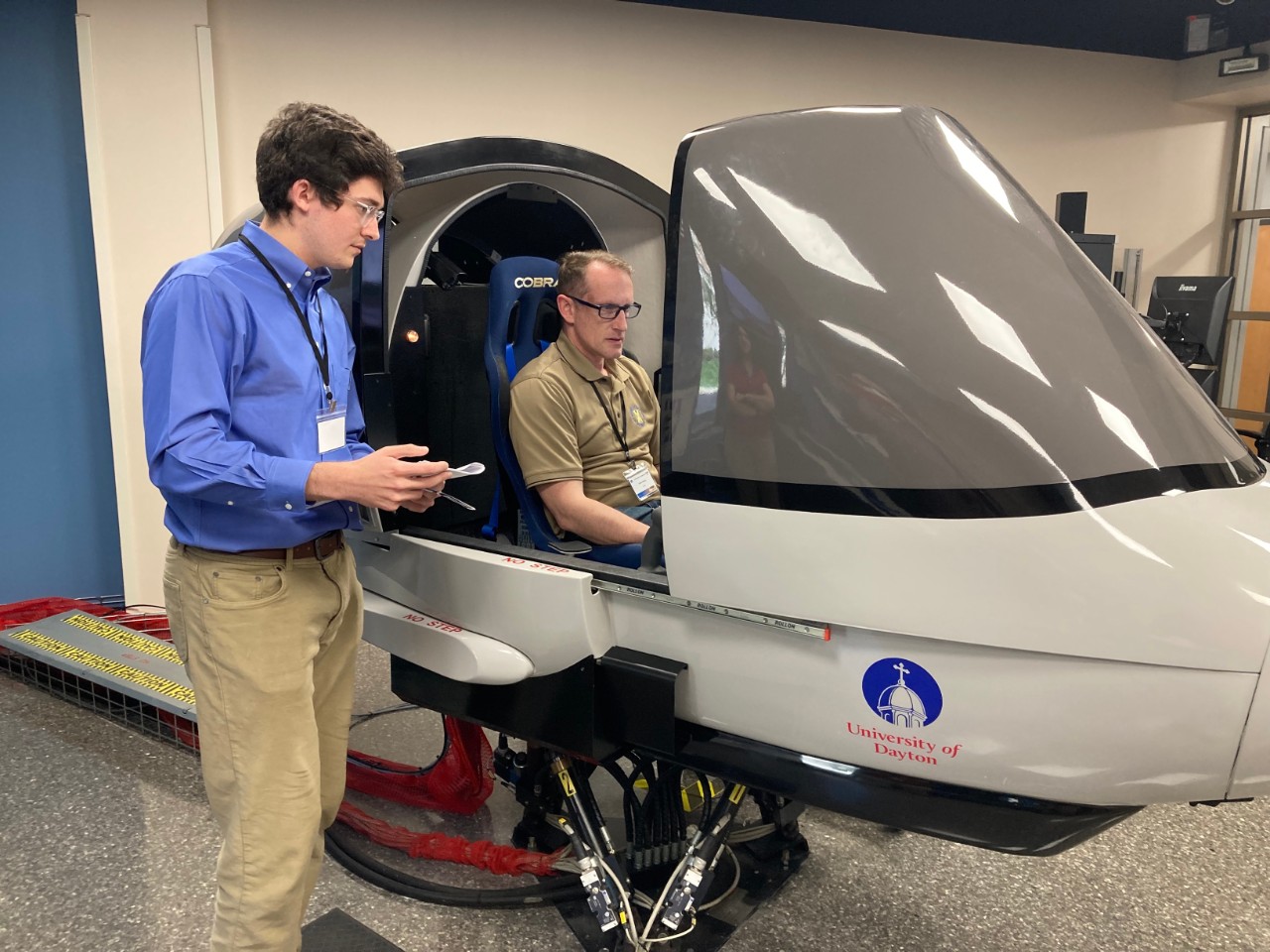 Liam Mckenna relays mission information to Frank Delsing during flight in a simulator.