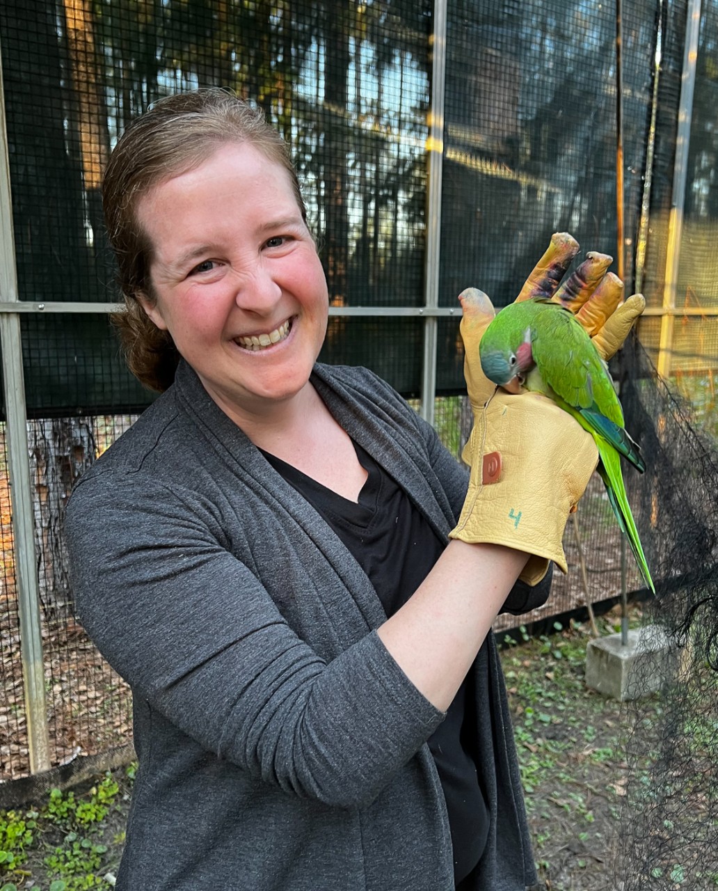 Elizabeth Hobson holds a parakeet in a gloved hand.
