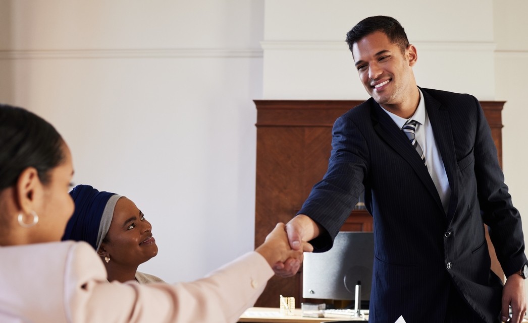 Law students at firm sitting at a table shaking hands