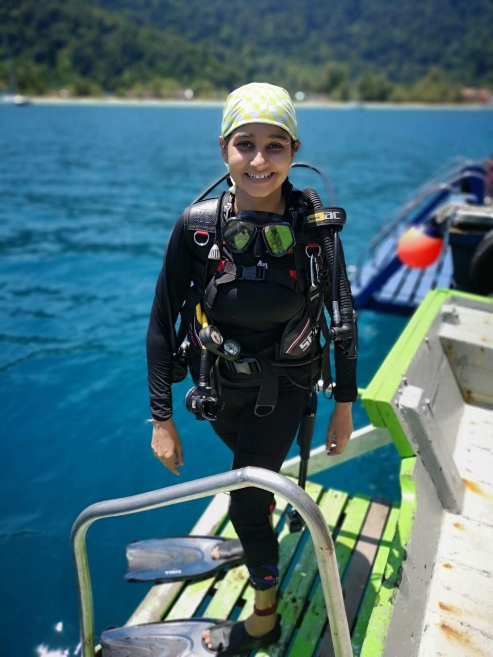 Radhika Bhargava stands on the edge of a dock wearing diving gear.