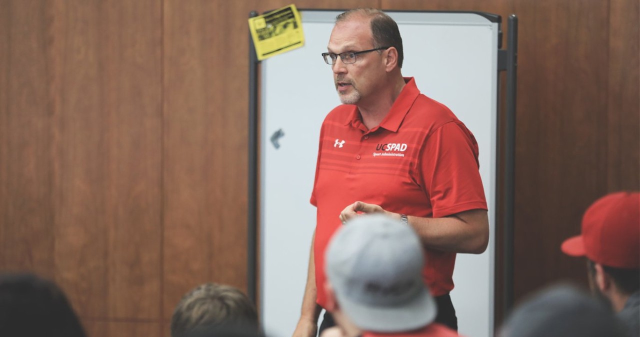 Photo of Dr. Kelley teaching with whiteboard in background.