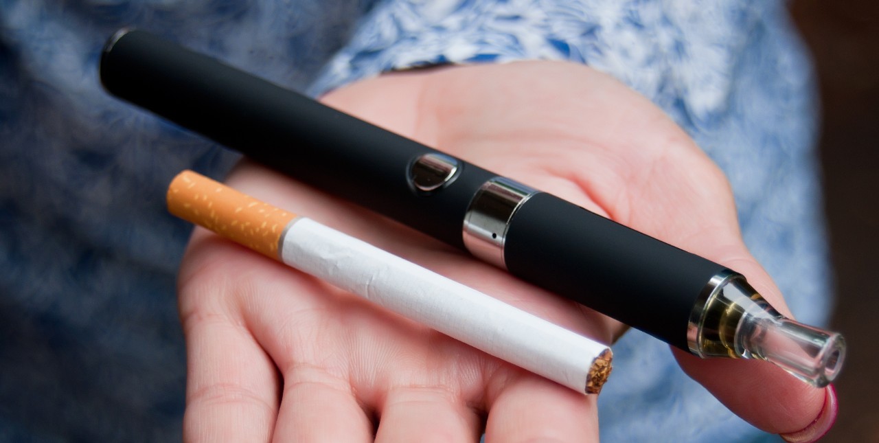 a vape pen and cigarette in the palm of a hand 