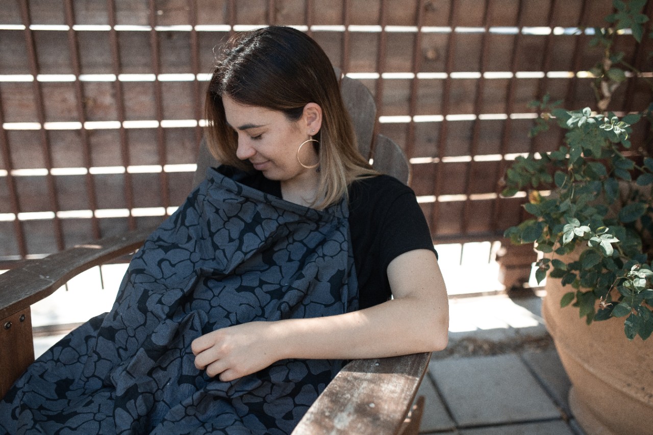 a photo of a woman breastfeeding with a blanket covering her body