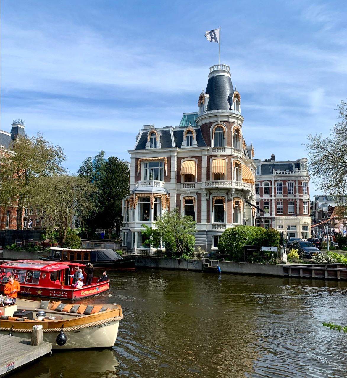 Beautiful building behind a river with boats in Amsterdam, Netherlands.