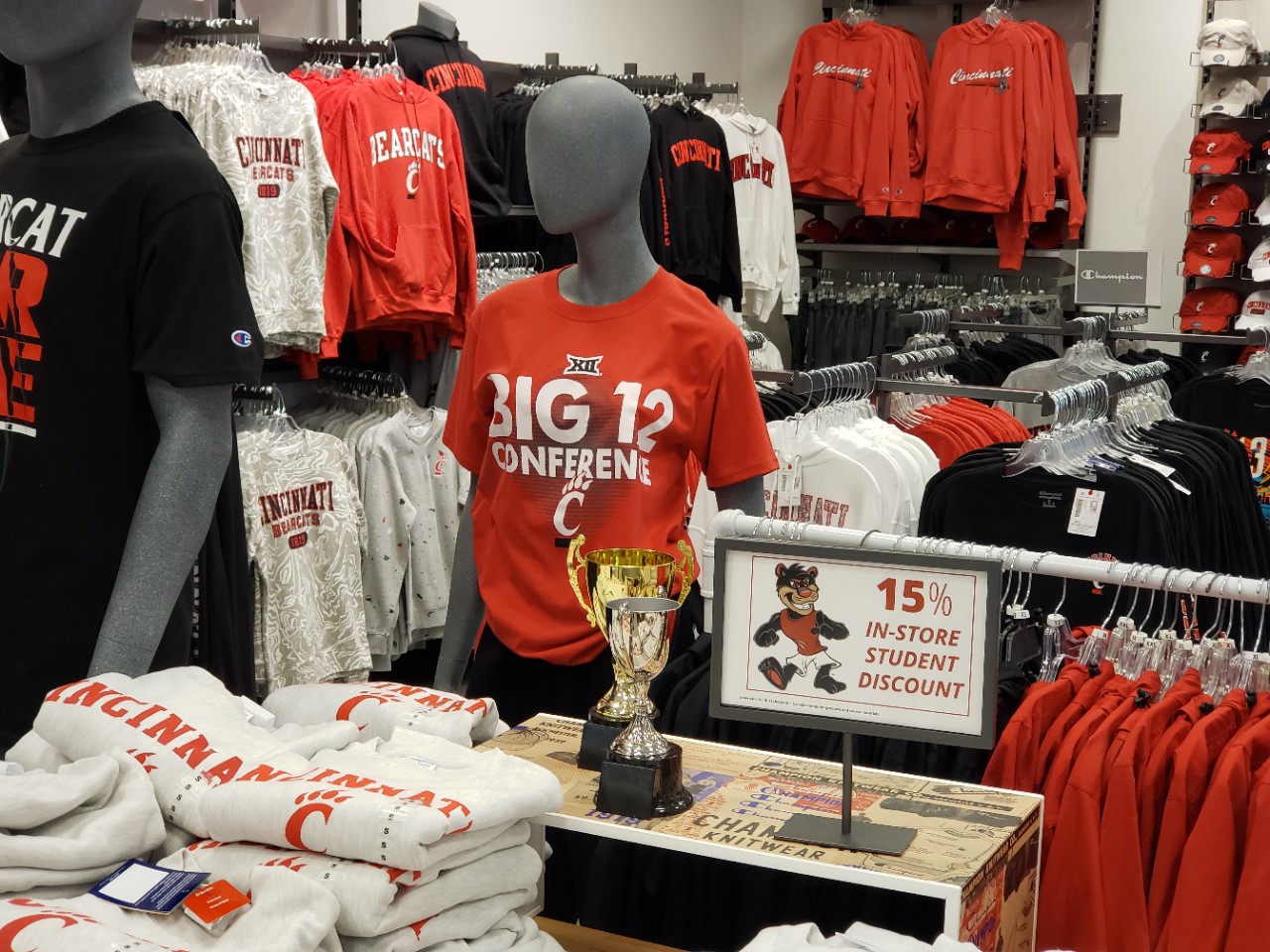 Image in the UC Bookstore of sweatshirts and t-shirts with Big 12 logo for UC Bearcats.