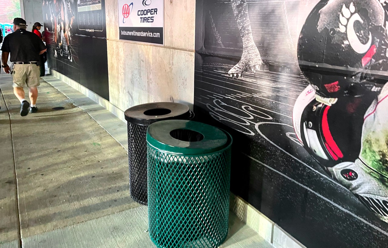 Two round cans (one black trash, one green recycle) inside UC's Nippert Stadium.