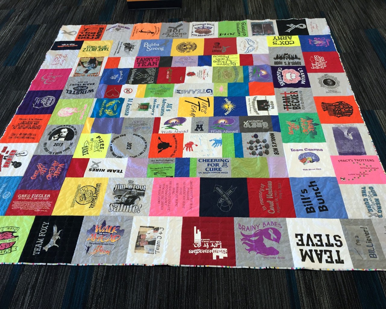 Large quilt made of squares from t-shirts emblazoned with team names in honor of brain tumor research.