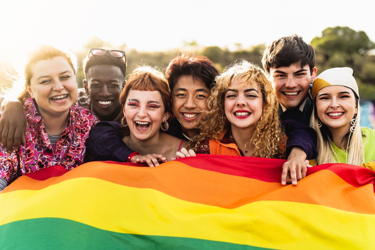 Group of individualls holding the representative LGBTQ flag. 