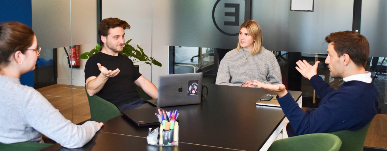 Young business entrepreneurs sit around table with laptops.