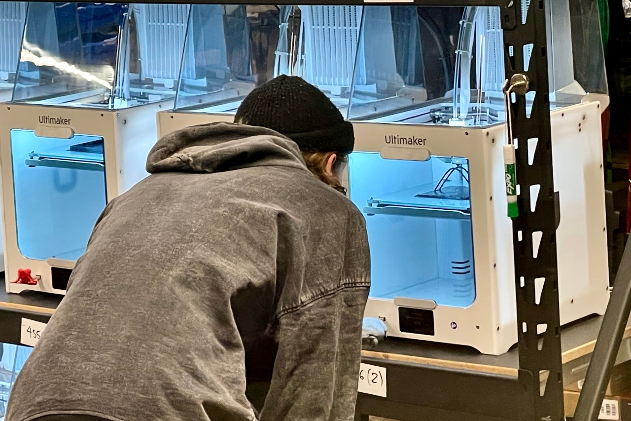 A student watches a 3D printer working in UC's 1819 iHub Makerspace.