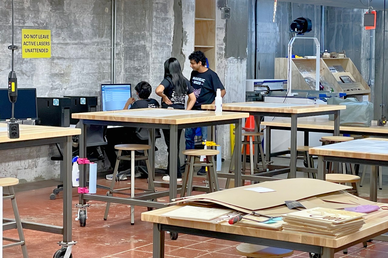 Students work on digital laser cutting machines in UC's 1819 iHub Makerspace.