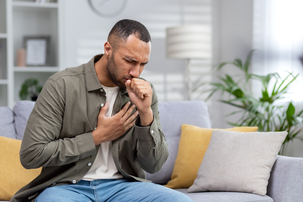 a man sitting on a couch coughing