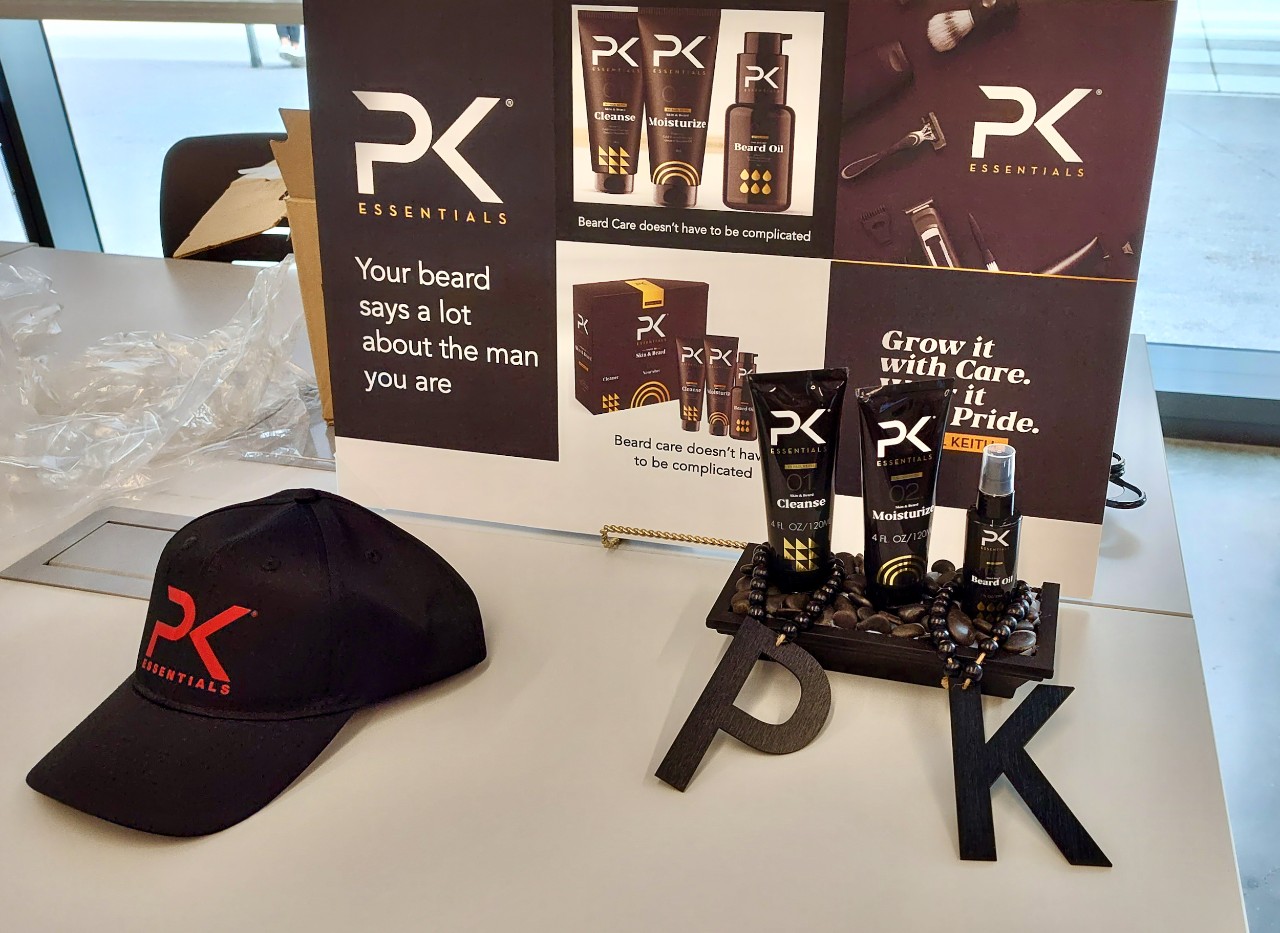 A poster, ball cap and beard oil products arranged on a table for promotion.