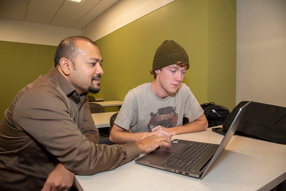 Professor working with a student on a laptop