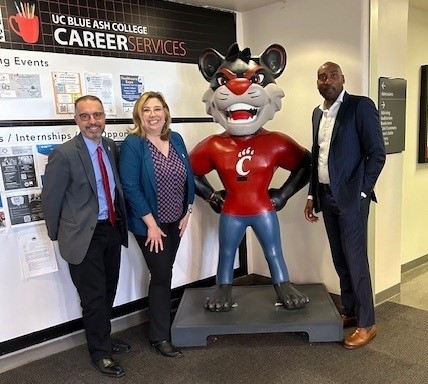 three people posing with bearcat mascot statue