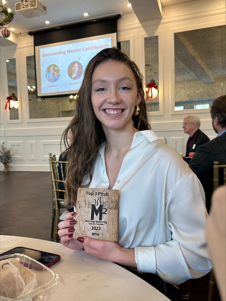 A woman seated at a table holds a plaque.