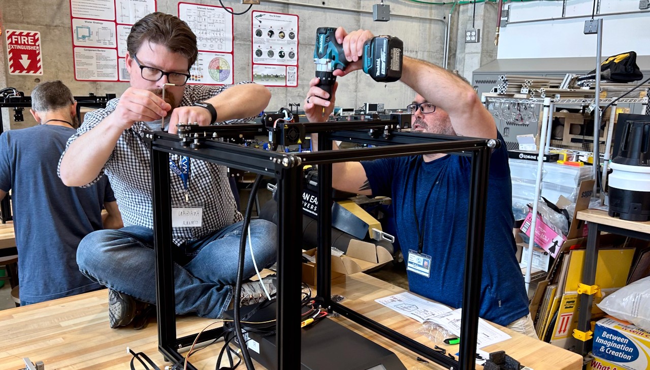 Two men assemble plastic #D frame with drills