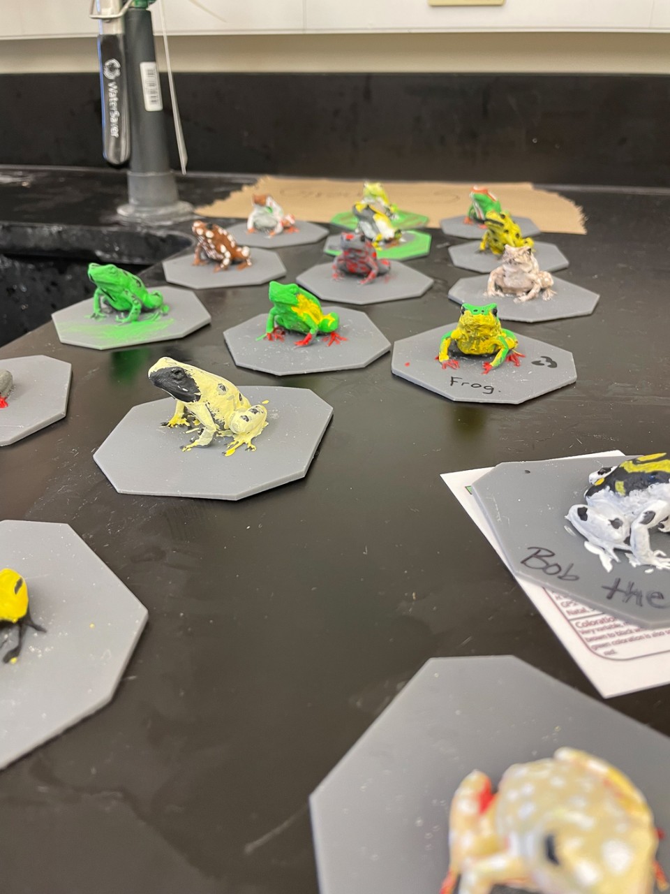 Colorful plastic frogs sit on a classroom table. 