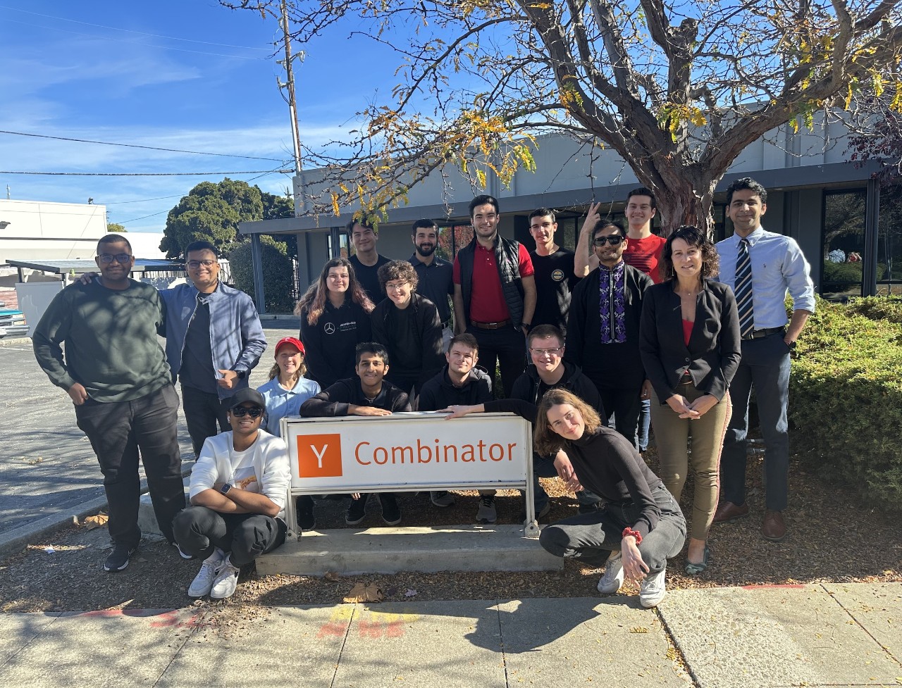 A group of students pose for a photo next to a sign for Y Combinator, an American technology startup accelerator.