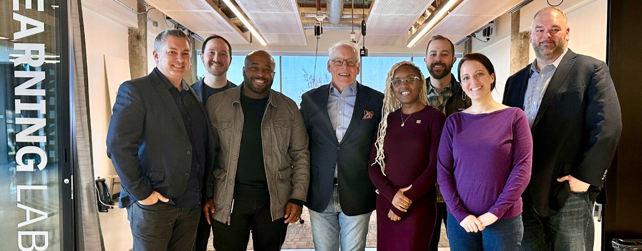 Eight men and women, members of UC's 1819 learning Lab, Fifth Third business leaders and UC faculty members stand in front of UC's Learning Lab.